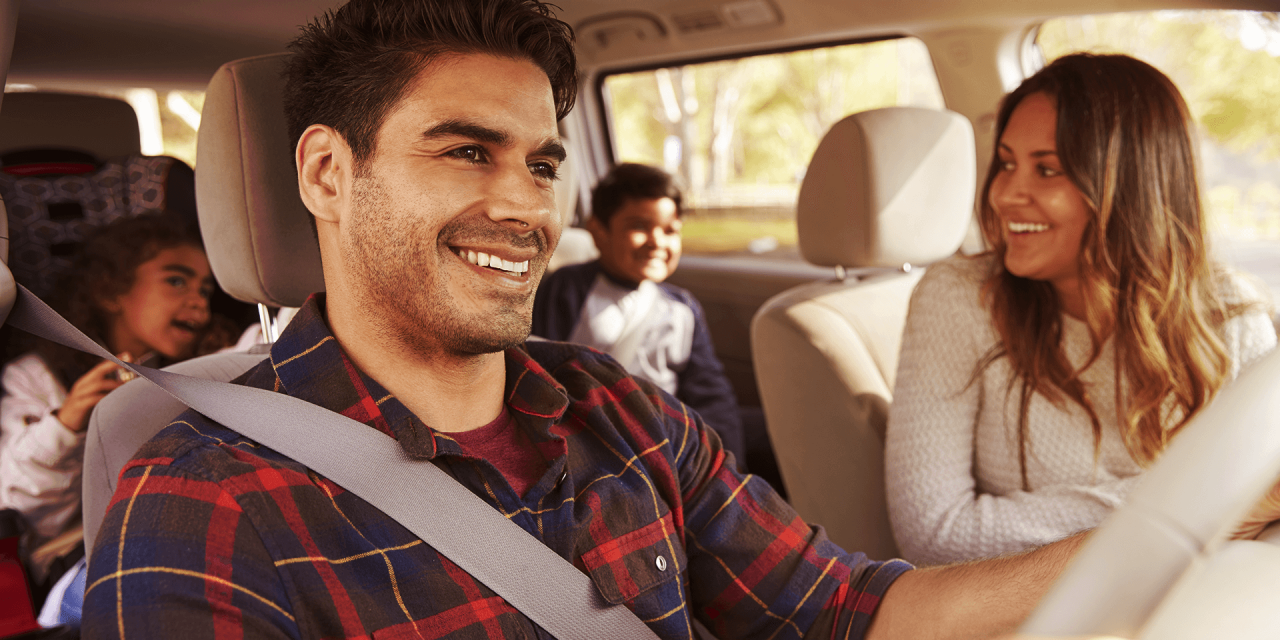 Man and woman in the fornt seat, driving their kids in the family.