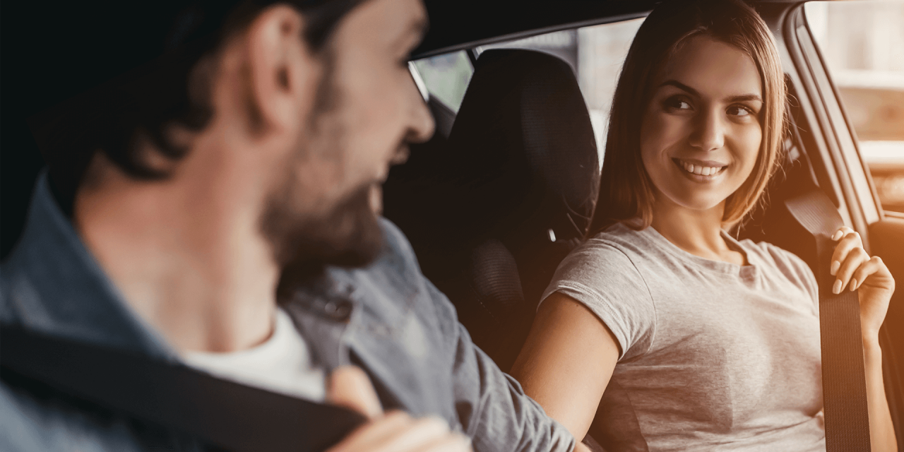 Couple adjusting their seatbelts inside vehicle.