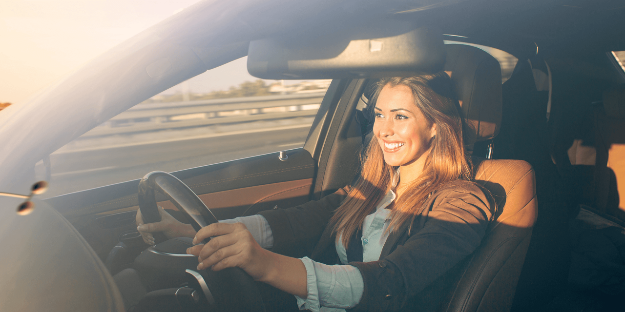 Lady with two hands on the wheel, driving her vehicle..